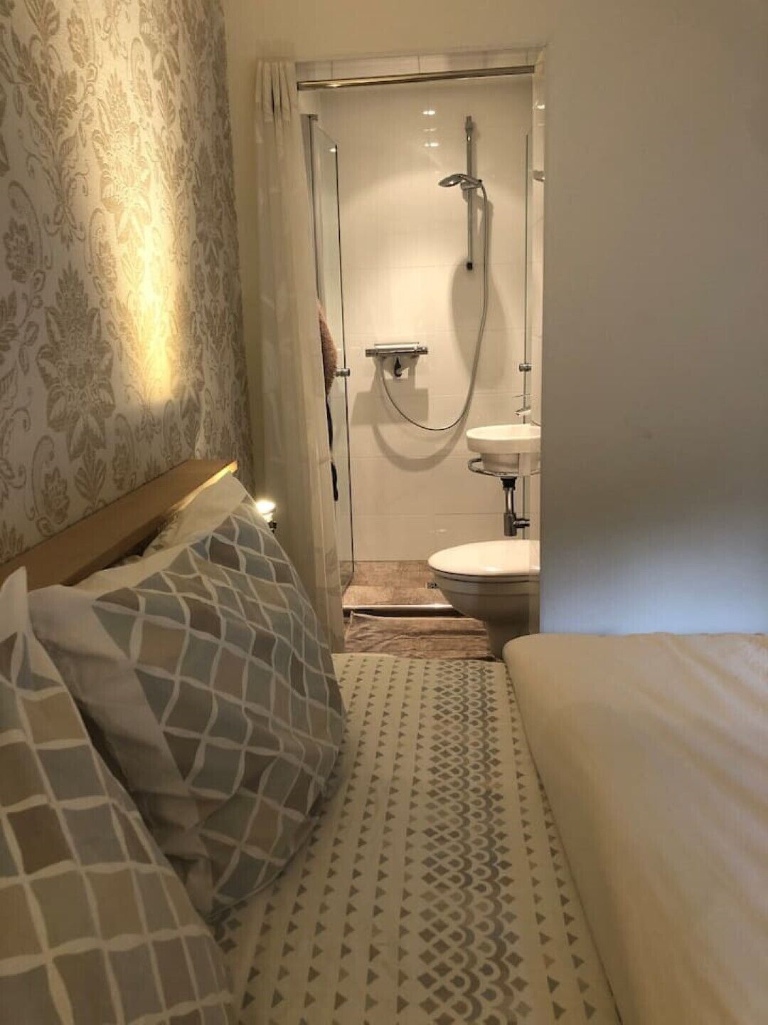 A hotel room with a bed, a shower, and a toilet.