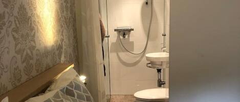 A hotel room with a bed, a shower, and a toilet.