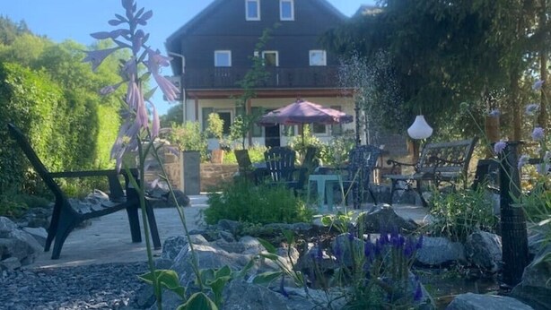 Ein Haus mit einer Terrassenfläche, umgeben von Steinen und Pflanzen.