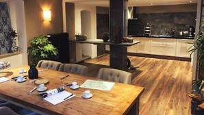 Eine moderne Küche mit dunkler Küchenrückwand, Holzboden und einem Essbereich mit Holztisch und -stühlen.