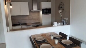 A compact kitchen with a dining area. It includes a microwave, stove, and cabinets. - Superb T2 Hyper center Le Touquet (Le Touquet-Paris-Plage)