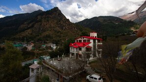 A building with a red roof, surrounded by mountains and a small parking area.