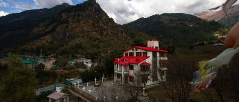 A building with a red roof, surrounded by mountains and a small parking area.