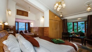A hotel room with a large bed, a wooden headboard, a seating area with a table, and a view of the outdoors.