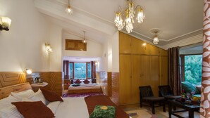 A spacious bedroom with a large bed, wooden wardrobe, and a seating area.