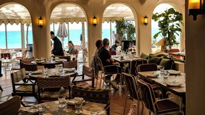 Un restaurante con terraza, mesas, sillas y vista al mar.