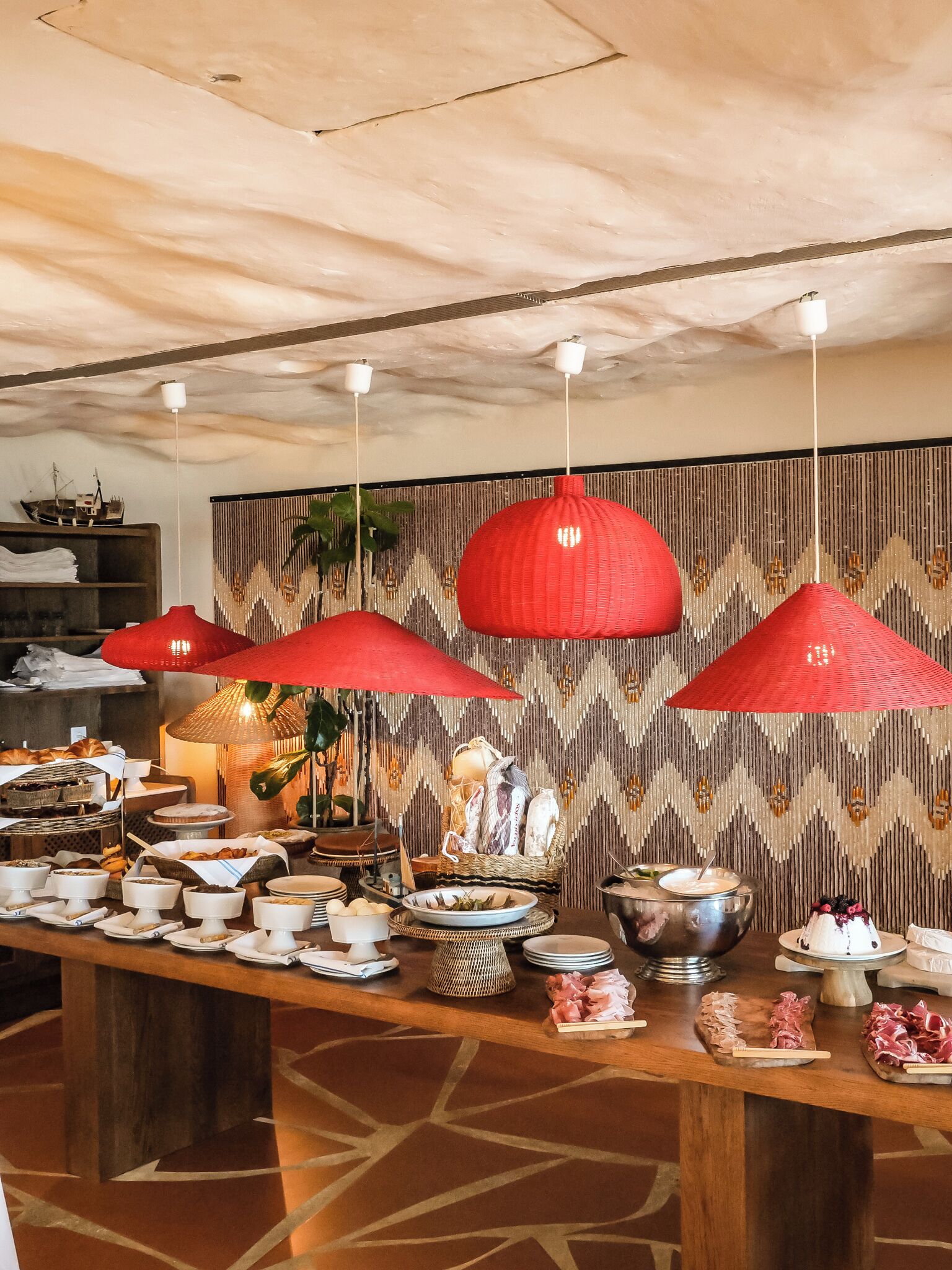 A buffet setup with various food items and a decorative wall in the background.