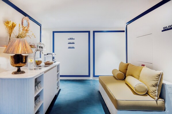 A modern hotel room with a white and blue color scheme, a sofa with yellow cushions, a decorative lamp, and a wall-mounted mirror. - Isabella's Llafranc (Palafrugell)