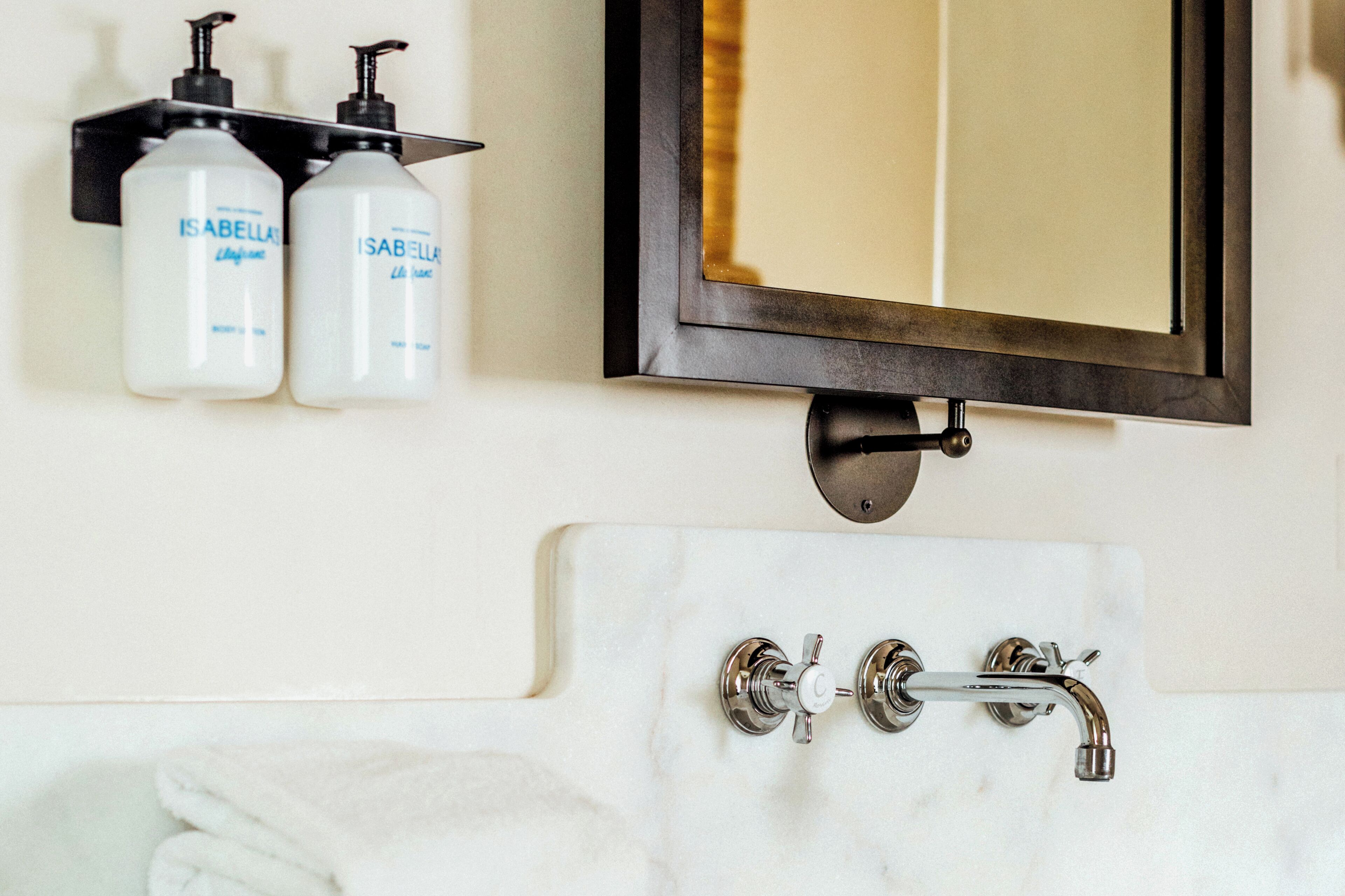 A bathroom with a white marble sink, two faucets, and a mirror with a black frame.