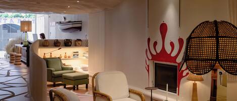 Uma sala de estar moderna com lareira, cadeiras de vime e piso estampado.