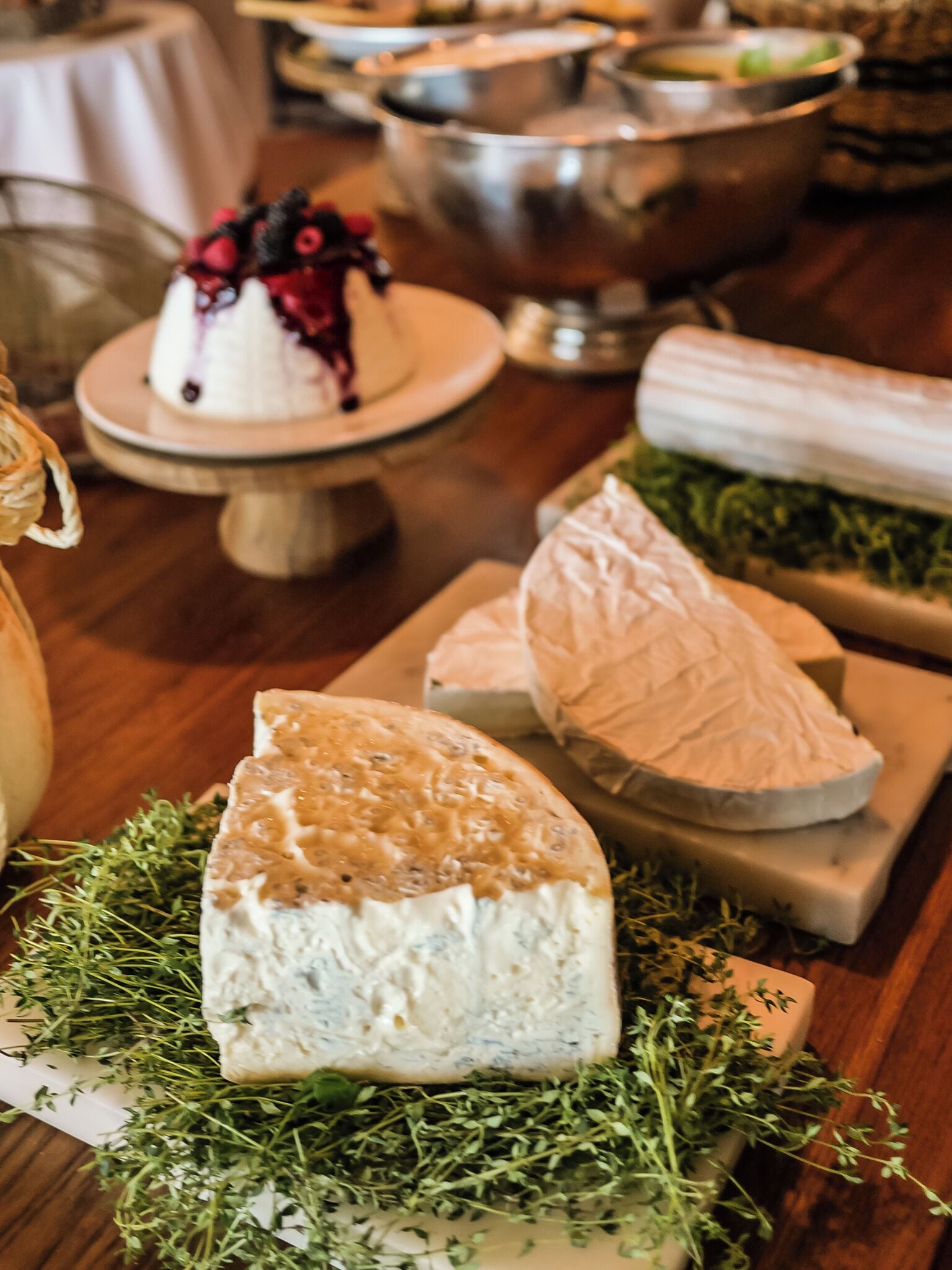 A variety of cheeses and herbs on a wooden table.