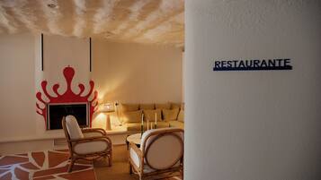 Una habitación acogedora con sofá, dos sillones, una mesa y una pared con un cartel que dice 'RESTAURANTE'.