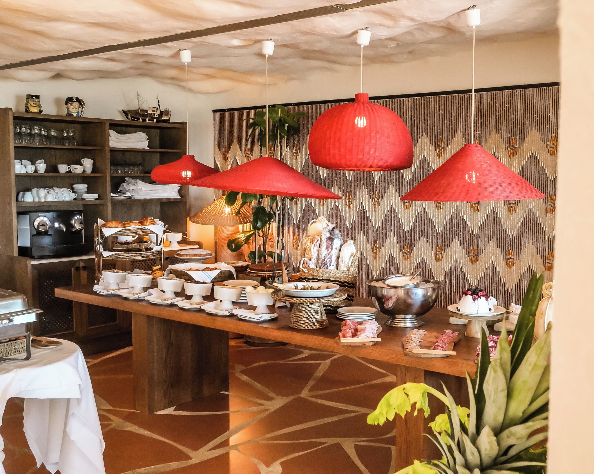 Montaje de bufé con diferentes opciones de comida, una máquina de café y una pared decorativa con patrones verticales.