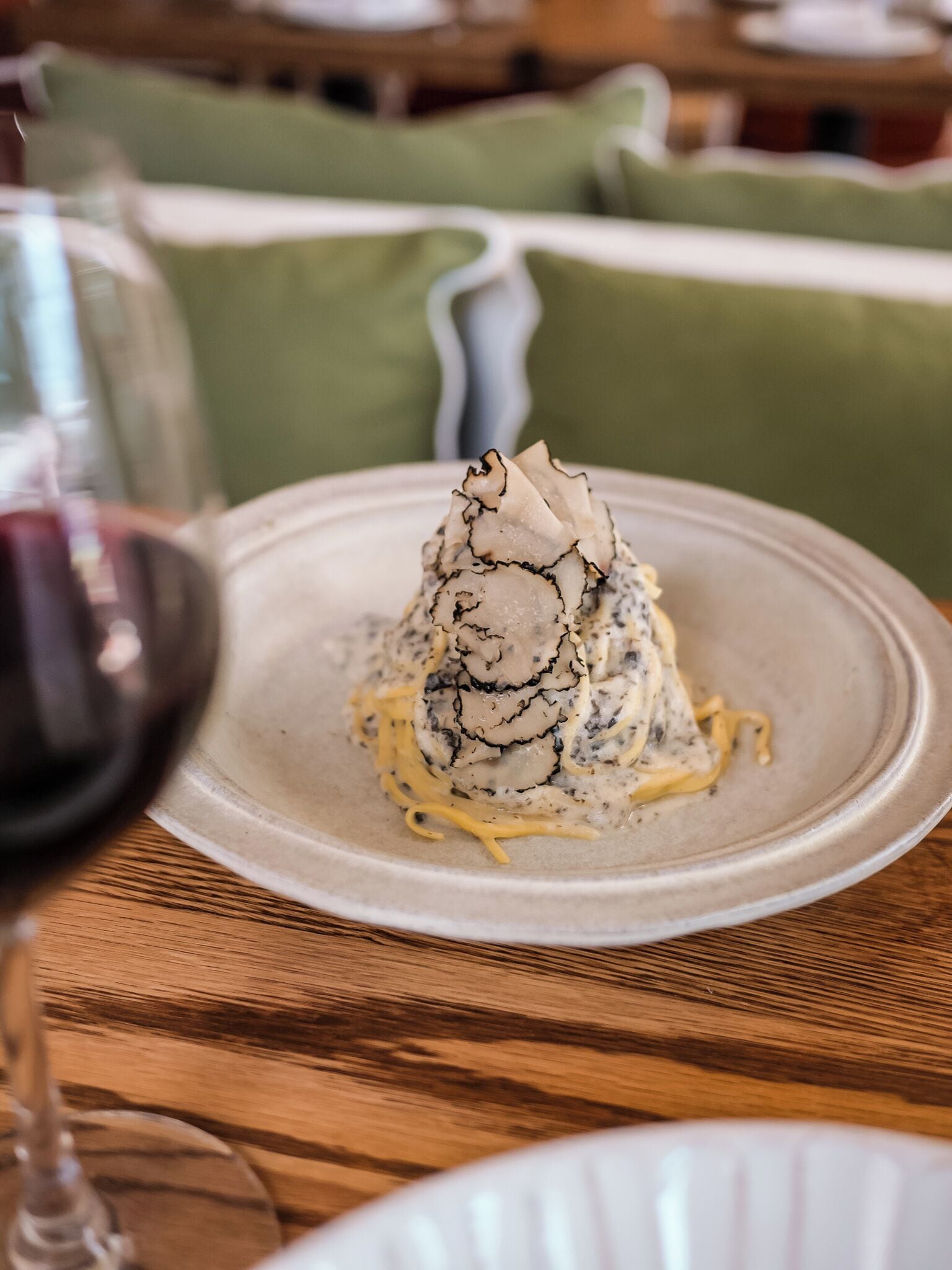A dessert on a plate with a creamy base and a dark topping, placed on a wooden table.