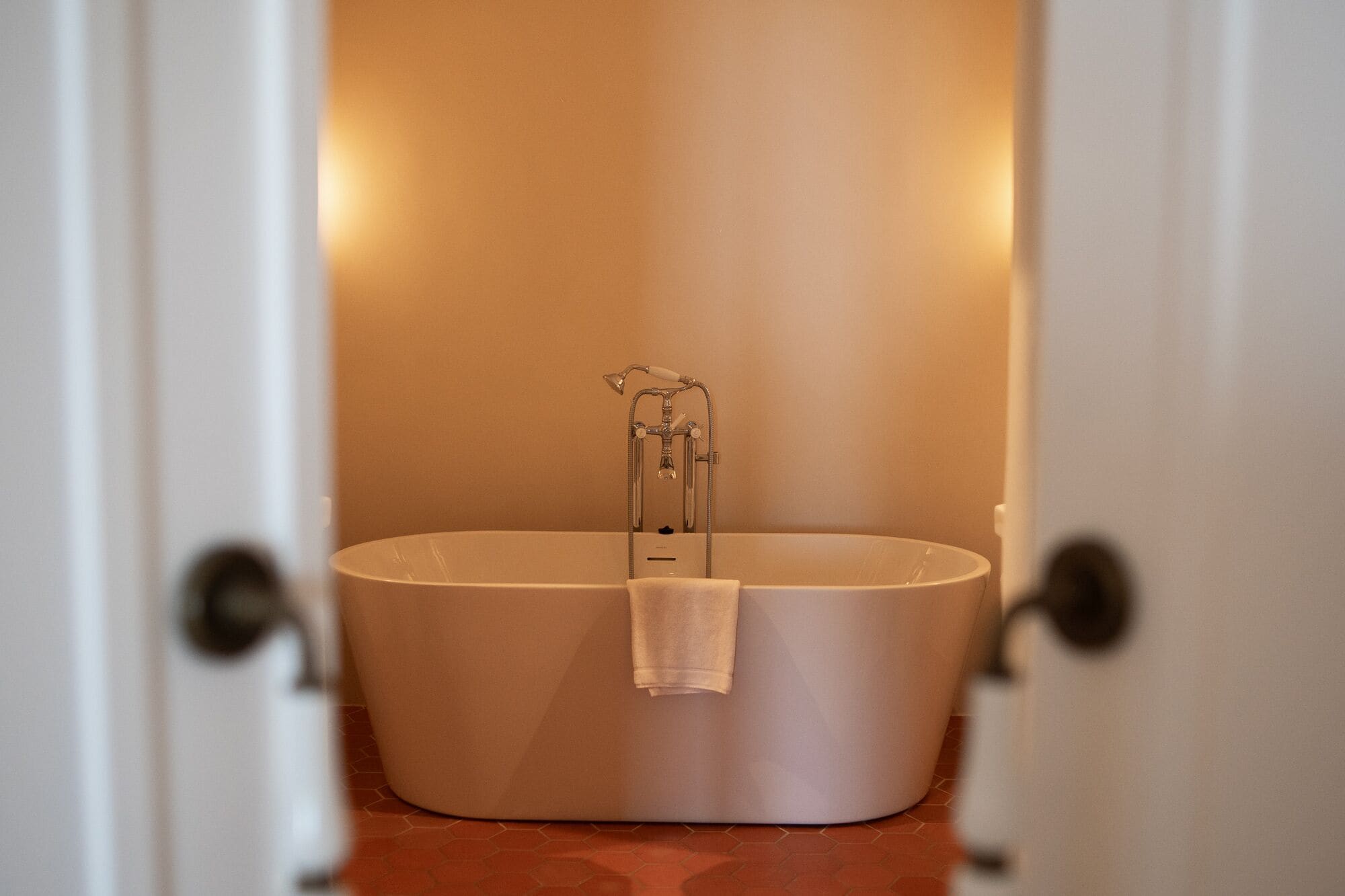 A modern bathroom with a freestanding bathtub, a towel hanging on the side, and a showerhead.