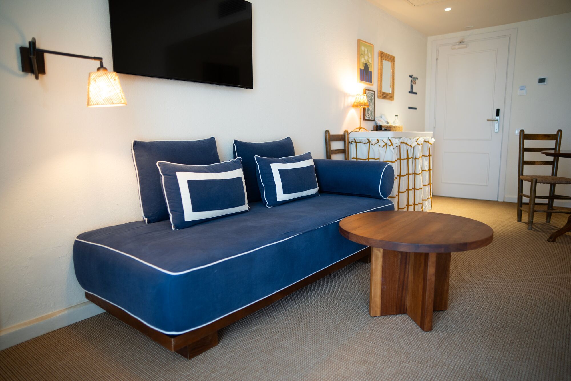 A modern living room with a blue sofa, a wooden coffee table, and a flat-screen TV mounted on the wall.