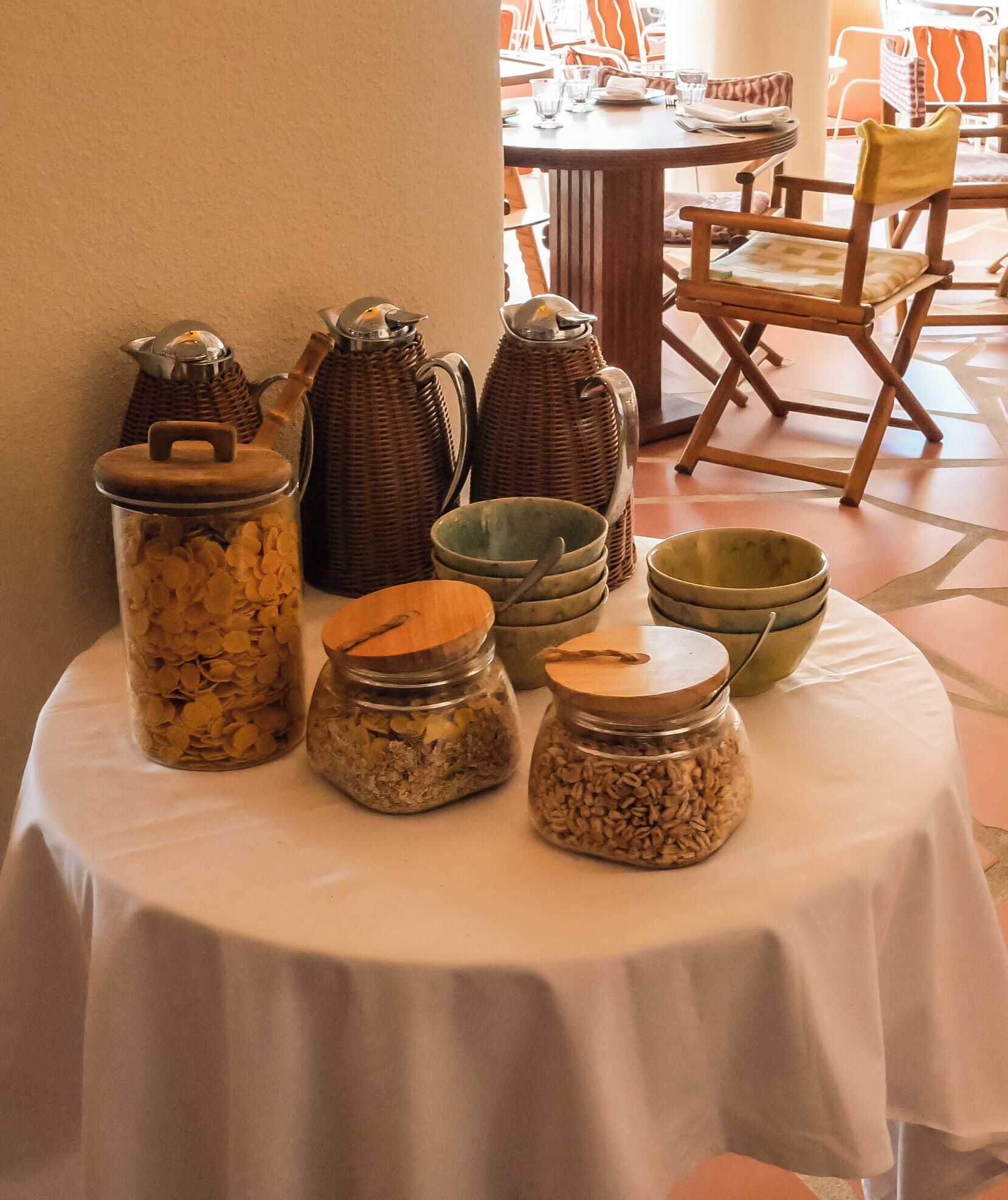 A table with various jars containing grains and seeds, surrounded by wicker baskets and wooden bowls.