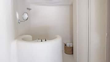 Un baño con una bañera blanca, un espejo instalado en la pared y una cesta de mimbre con toallas.