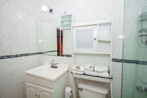 A bathroom with a white sink, a mirror, a glass shower enclosure, and a towel rack. - Ocho Rios Studio Ocean View (Ocho Rios)
