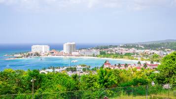 Un paysage urbain côtier offrant une vue sur l’océan, un port de plaisance et plusieurs immeubles de grande hauteur.