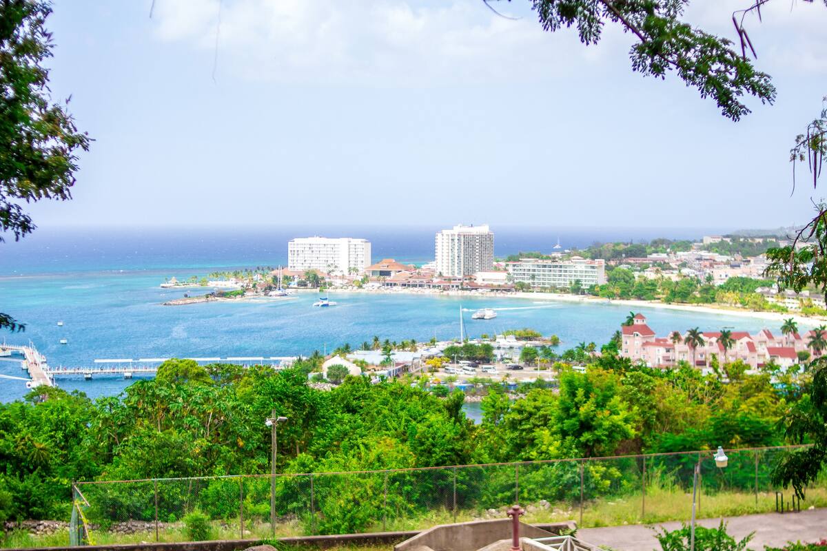 A coastal cityscape with buildings, a marina, and a bridge.