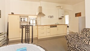 Una cocina moderna con una isla central, un comedor con mesa y sillas, y una sala de estar con un sofá estampado de cebra.