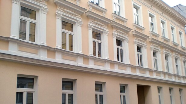 Un edificio de varios pisos con fachada color crema y detalles blancos en ventanas y puertas.