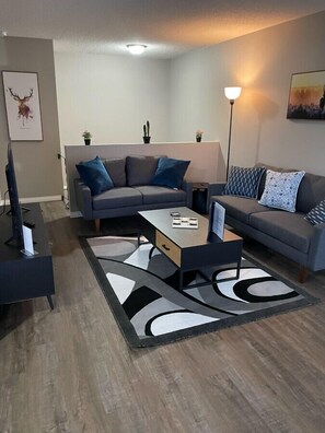 A modern living room with a sectional sofa, a coffee table, and a TV stand. - Wonderful 2-bedroom apartment (Camrose)