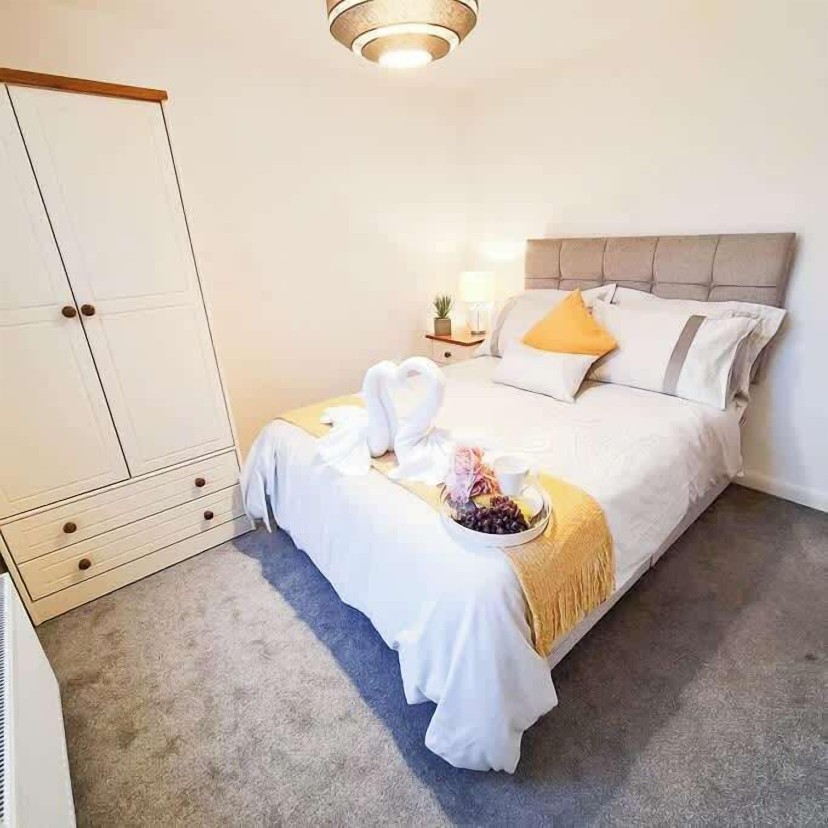 A hotel room with a bed, a wardrobe, and a nightstand with a lamp.