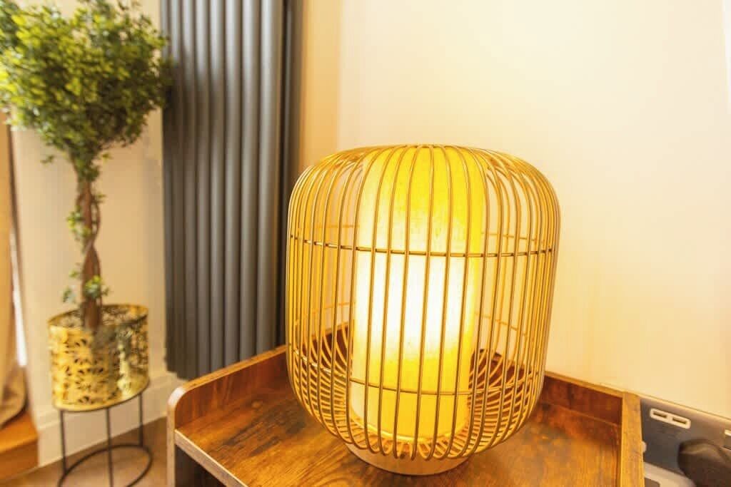 A room with a wooden table, a potted plant, and a decorative lamp.