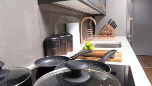 Una cocina moderna con electrodomésticos de acero inoxidable, una tabla de cortar de madera y un bloque para cuchillos.