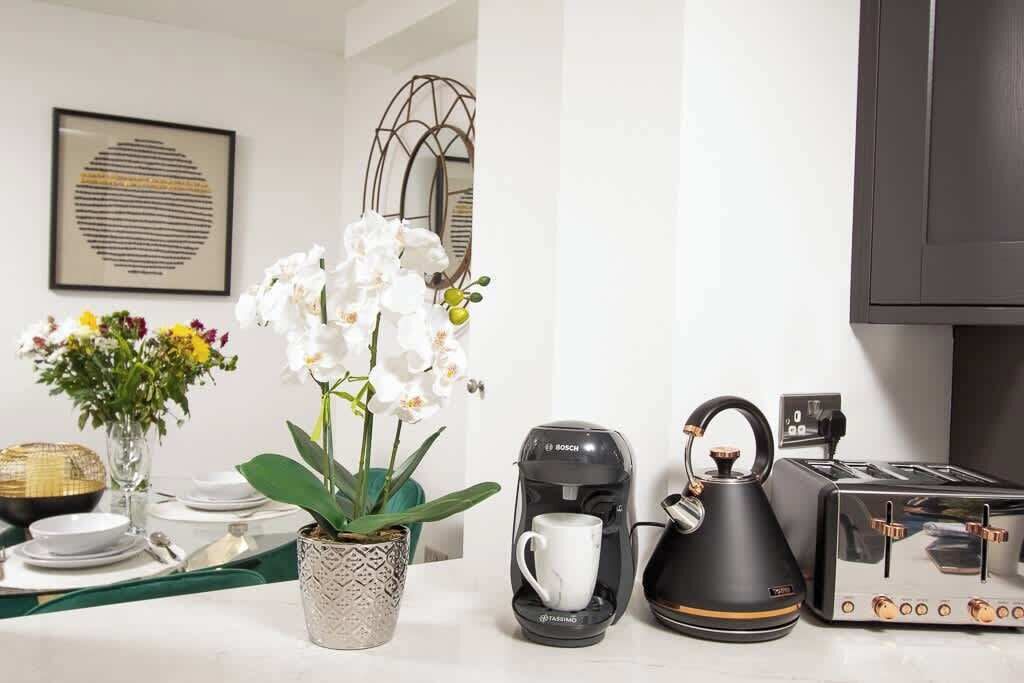 Una cocina con cafetera, hervidor y tostadora sobre la encimera.