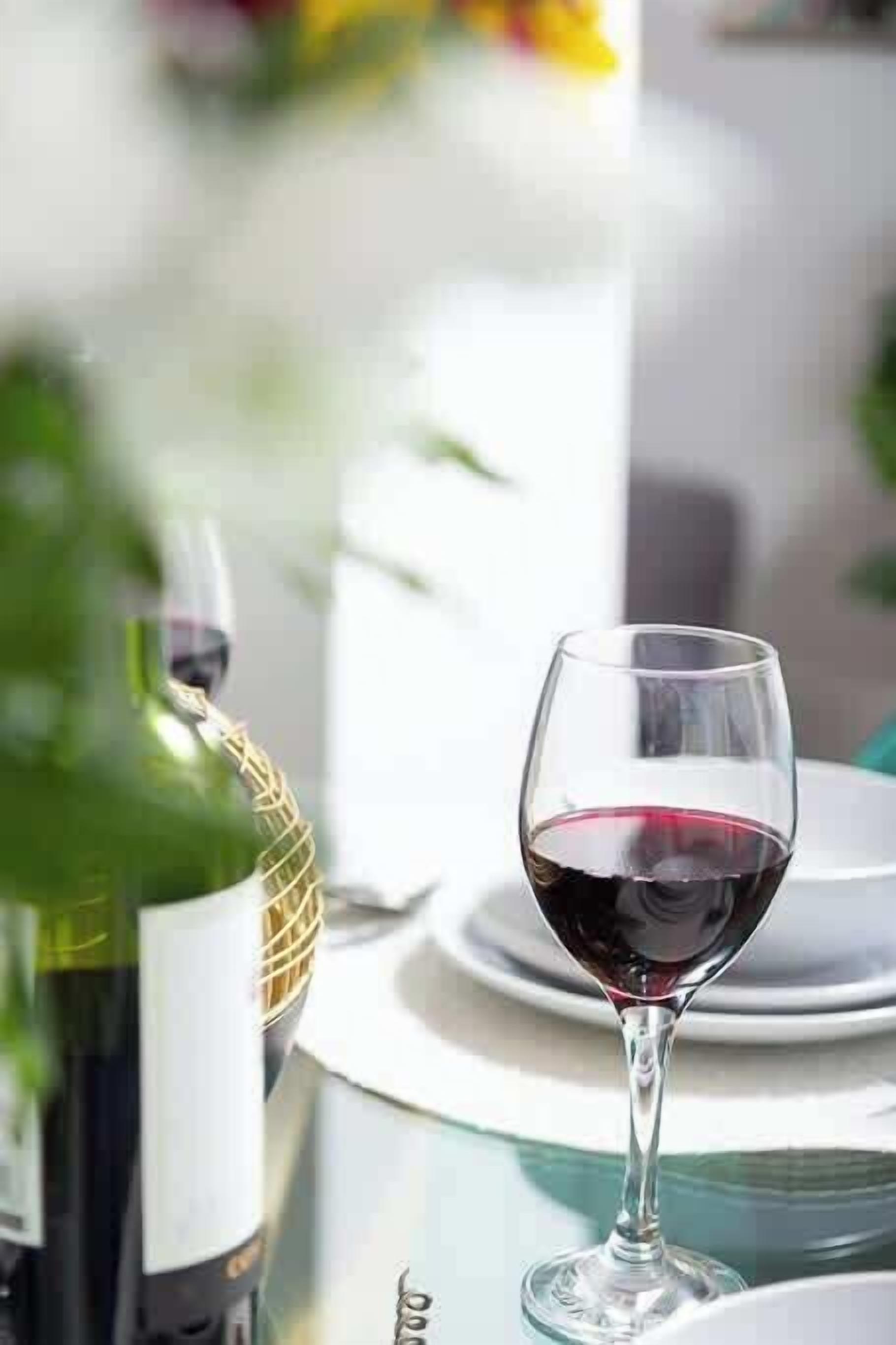A wine bottle and a glass of red wine on a table.