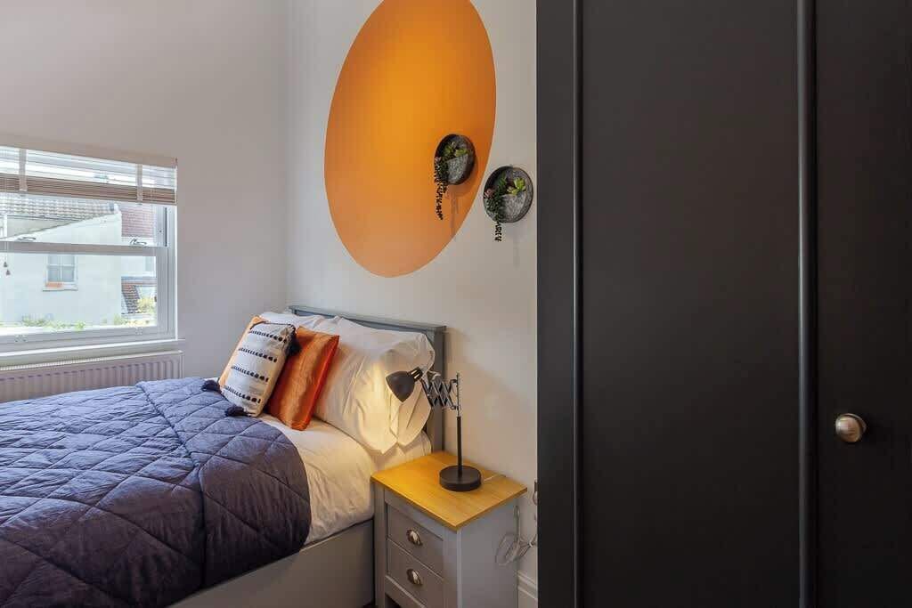 Ein Schlafzimmer mit Bett, Nachttisch, Lampe und Wanduhr.