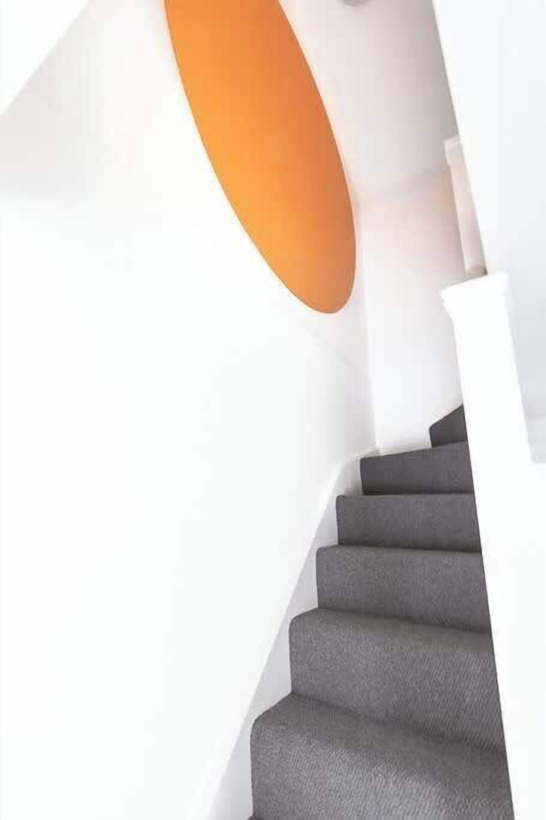 Un escalier avec des marches grises et un mur blanc.