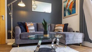 A modern living room with a grey sofa, a glass coffee table, and a floor lamp.