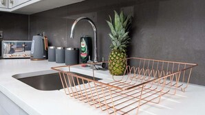 A modern kitchen with a copper wire rack, a pineapple, and a coffee maker.