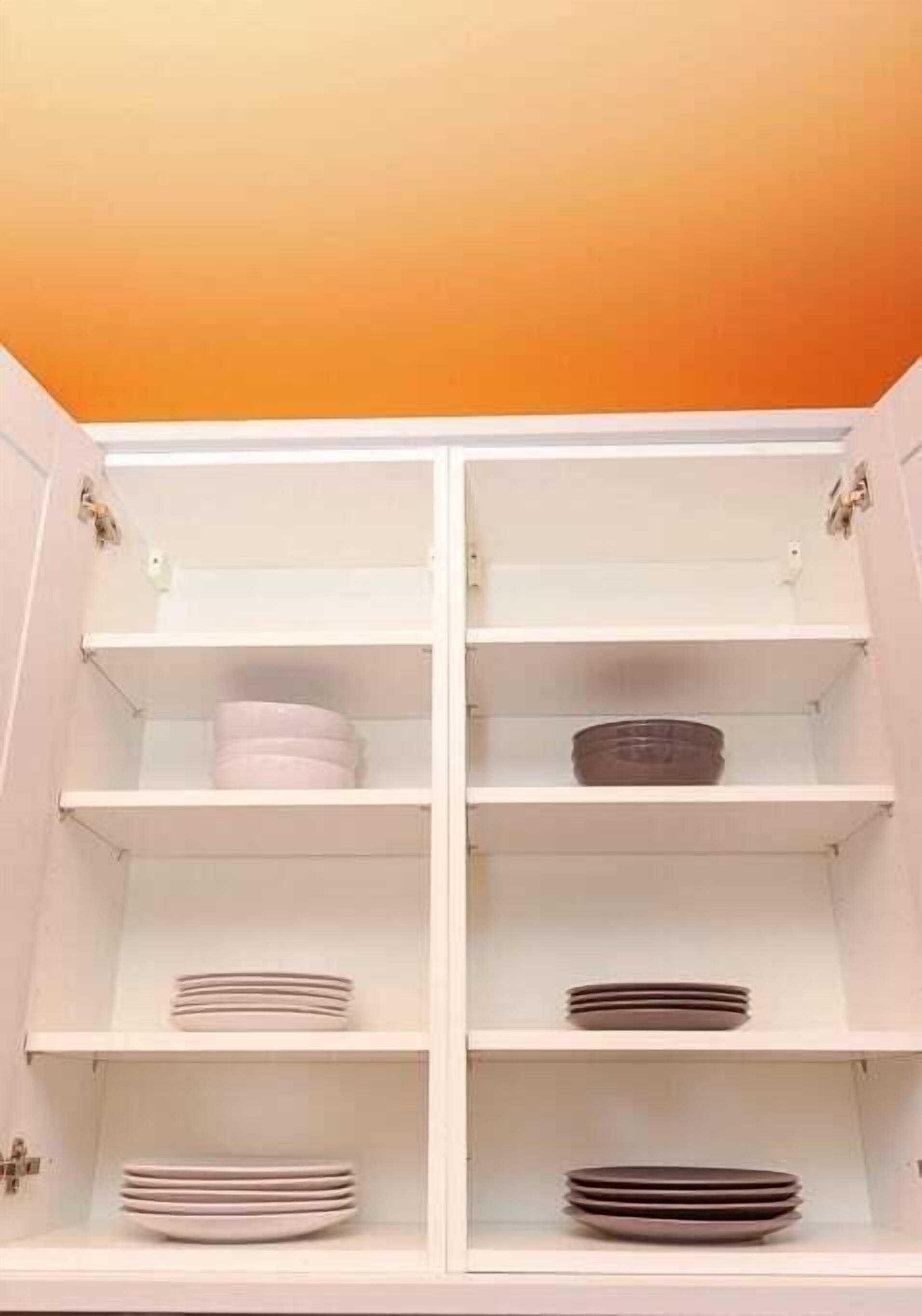 A white cabinet with multiple shelves, some containing stacked plates.