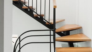 Una escalera moderna con escalones de madera y barandillas de metal negro.