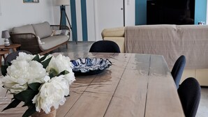 Un comedor con una mesa de madera, flores blancas y un plato con borde azul.