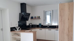 Una cocina moderna con armarios blancos, una campana extractora negra y una mesa de comedor de madera con sillas.
