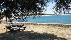 Una playa con una mesa de picnic de madera y un muro de piedra.