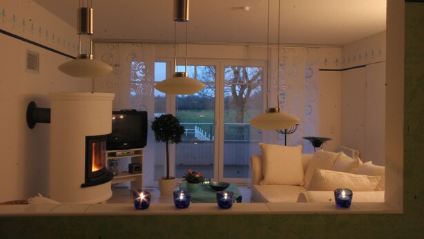 A modern living room with a fireplace, sofa, and decorative candles. - Hof Eckhorst, Apartment Baltic Sea (Güby)