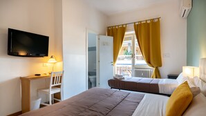 A hotel room with a bed, a desk, a chair, a television, and a window with curtains. - Aurelia Home Guest House (Rome)