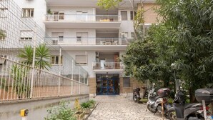 A multi-story residential building with balconies, a stone-paved courtyard, and parked scooters. - Aurelia Home Guest House (Rome)