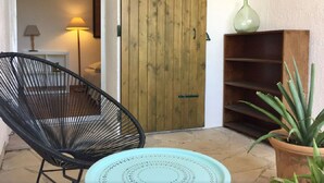 Une pièce avec une porte en bois, une chaise noire, un plateau turquoise, une plante en pot et une lampe.