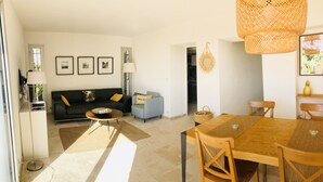 Un salon moderne comprenant un canapé, une petite table, une table à manger avec des chaises et une lampe.