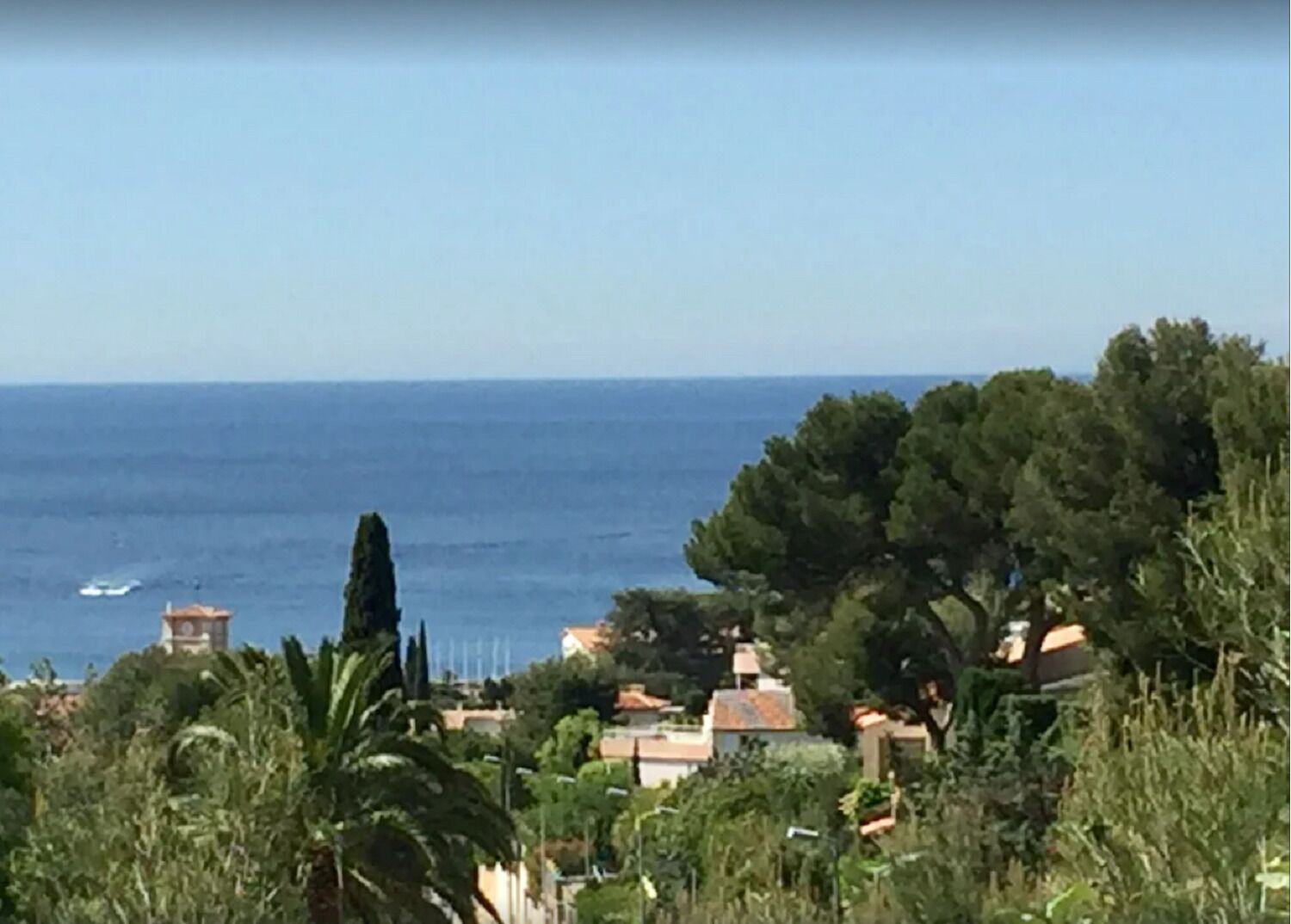 A coastal town with buildings, trees, and the sea.