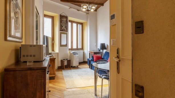 Una habitación con techo de madera, una mesa de comedor con sillas, un radiador y una mesita auxiliar.