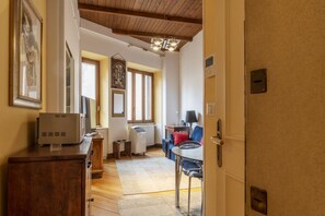 A room with a wooden ceiling, a dining table with chairs, a radiator, and a small side table.